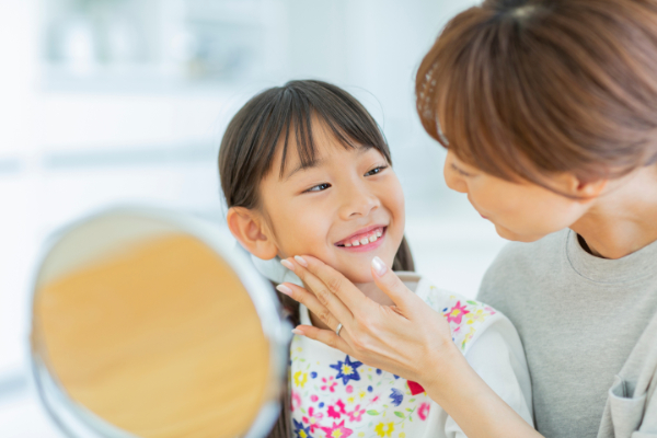 子どもの歯科検診が重要な理由として口腔内の問題を早期発見するため子どもの歯をチェックする母親